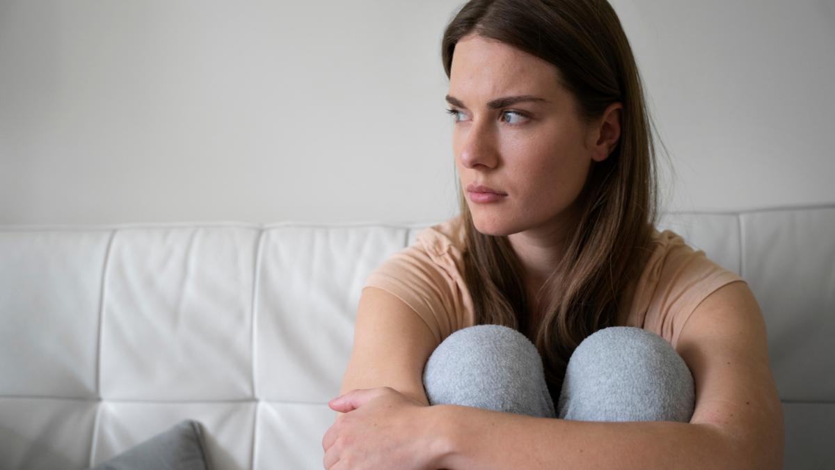 Взволнованная обиженная женщина на диване, вид спереди