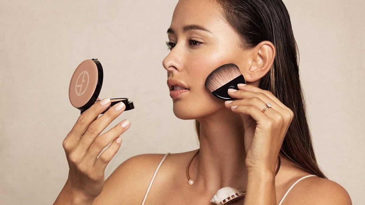 Девушка наносит пудру на лицо