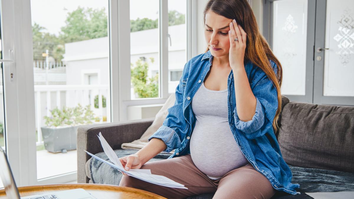 Беременная женщина перед ноутбуком с документами в руках