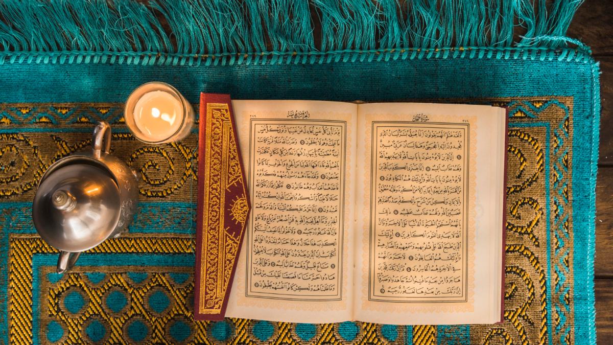 открытая книга на арабском языке с горящей свечкой