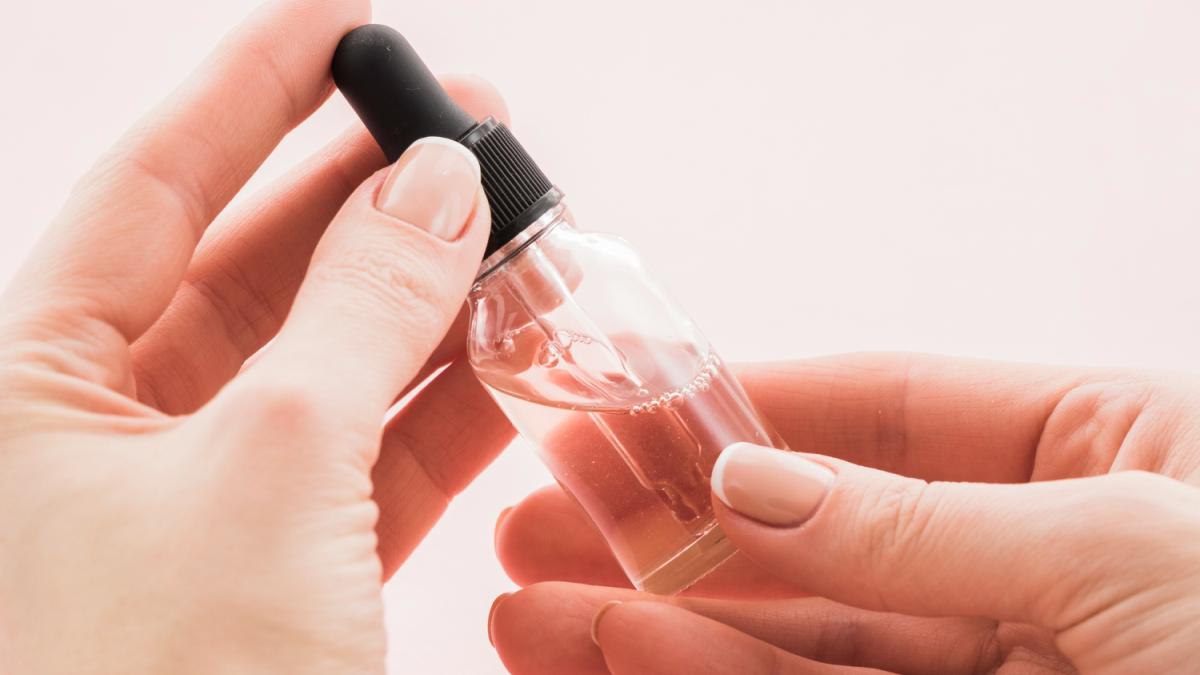 Руки держат сыворотку для лица