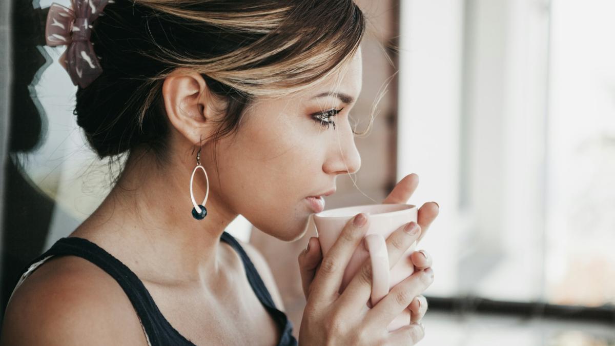 Женщина с чашкой кофе у окна