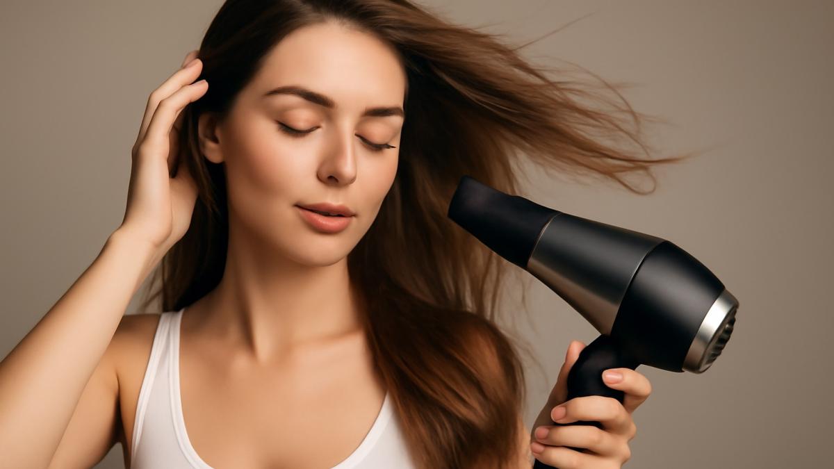 Девушка сушит волосы феном